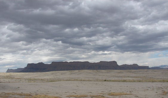 Storm clouds gather over a desert mesa.